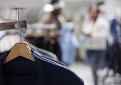 Trendy jackets on hangers in clothing store with blurred background. Casual modern blazers from new collection hanging on rack in department shopping mall close up selective focus