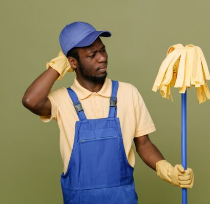 confused holding mop young africanamerican cleaner male in uniform with gloves isolated on green background SSUCv3H4sIAAAAAAAACpyRz27DIAzG75P2DhHnRmpC06R7lWoH8ycNKoUKSKep6rvPQKg474Z/tj/7M8/Pj6YhDLzi5Kt5xghjpfXqg4OgrEG8323cSSOkq8nD0eO+BlKoYJ0CXUMGgS8GbhKhWbWO+JWSxAcIq5c+Tt8QhyAvqJHhWyKveM5xUxIpiR2YImRXMb+yxArK4v/qzI/v4gYu0vDftHBlxEktIRs551Jy/QnS3WprsAplK1cPy0HHAlop3Z3iylyqNhuWdPbSxu1qgosrvDcn2to7MB1PPKOmLHwB77FcFF4N4vjJ9lbNMTYkA5sqEfgTMexofxpPh6nfD/2xG6dp3Ary7y0KddI6RQhjflWitq7iBoR28zAPjLcjo3N7GJhoTzAPLe0nKtiBT9ANePjXHwAAAP//AwCMxW5+mAIAAA==